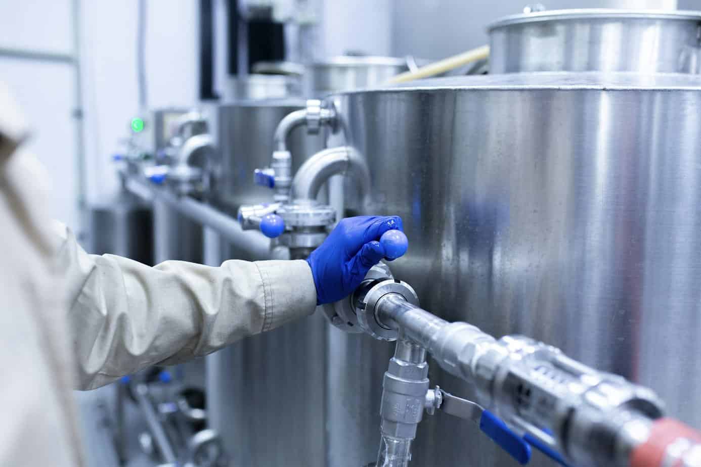 worker's hand turning the water valve of a pipeling on the factory